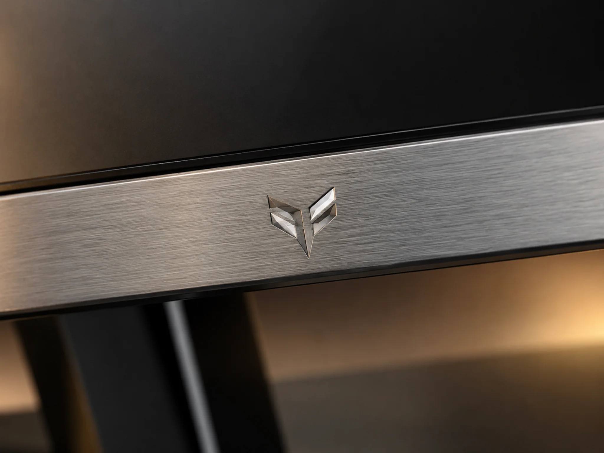 Machined polished metal logo detail on a monitor trim surface