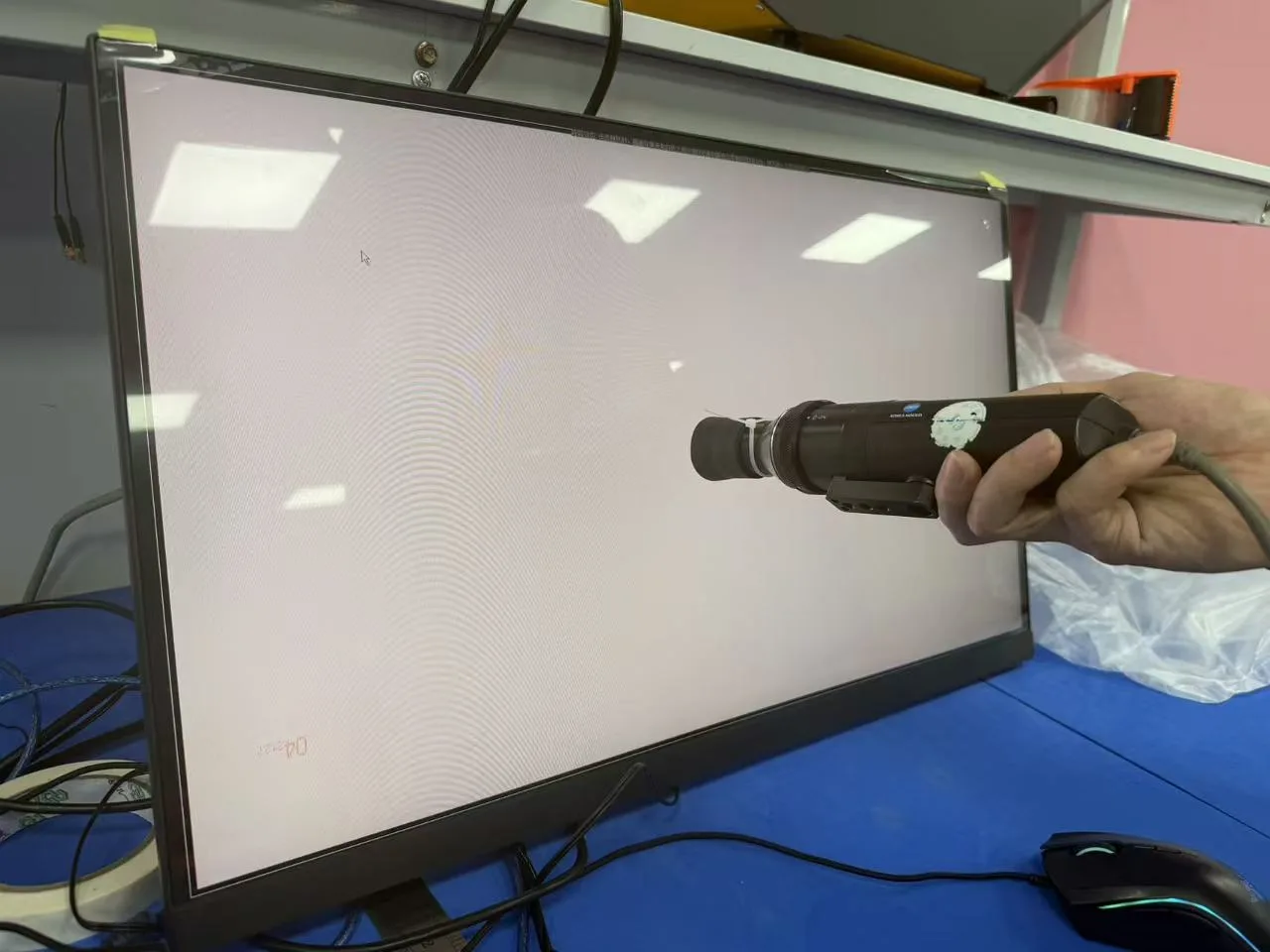 Side view of a measuring probe positioned in front of a white monitor screen